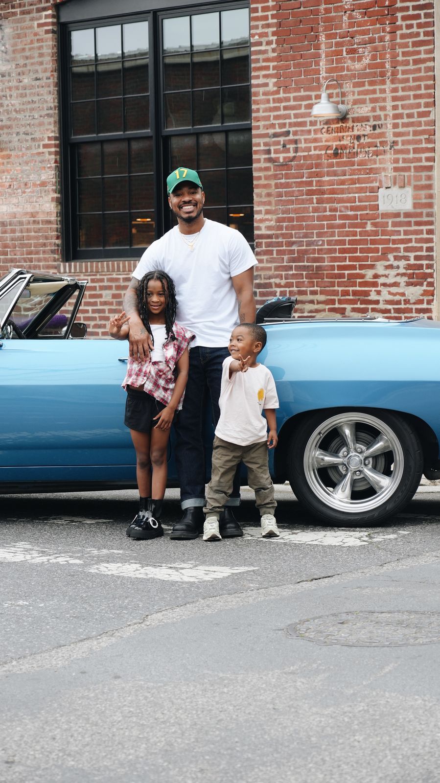 Rashiid Marcell with his kids beside a classic car